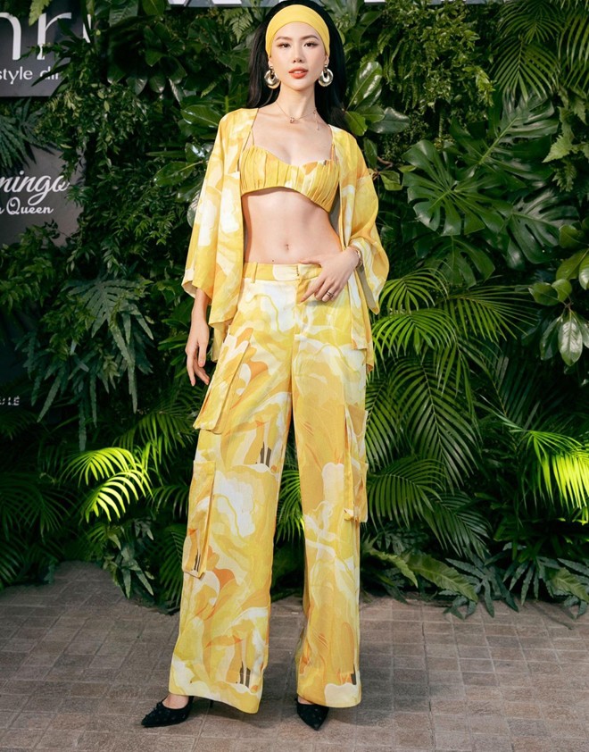 Miss Universe Vietnam 2023 Bùi Quỳnh Hoa diện set đồ có họa tiết hoa nhiệt đới cùng tone vàng rực như nắng hè để khoe khéo eo thon thả. Chọn layout make-up tone cam và dùng khăn như phụ kiện tinh tế để tạo điểm nhấn cho mái tóc.